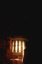 a woman standing in sunlight through an old window in an ancient cellar 