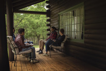 teen boys sitting on a cabin porch discussing scripture 