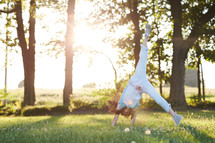 a girl doing a cartwheel in the grass