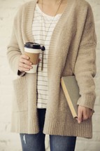 woman holding a paper coffee cup and Bible 