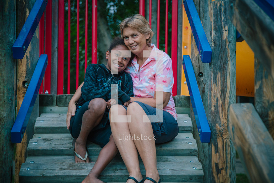 a woman hugging a girl on playground equipment
