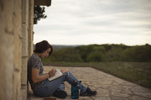 teen girl sitting outdoors reading a Bible 