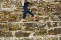 woman walking at the edge of a stone wall in heels 