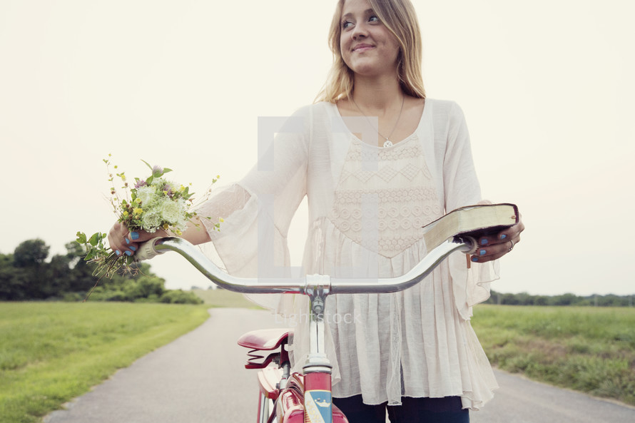 woman riding a bicycle holding a bible and flowers 