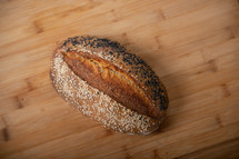 craft bread is sprinkled with white and black sesame seeds on a wooden background with copy space