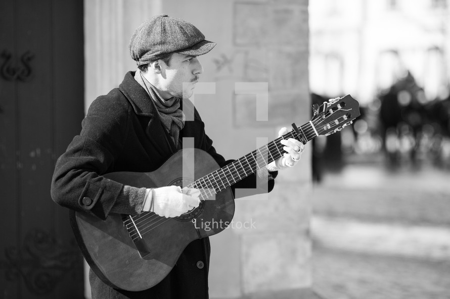 man playing a guitar on a street corner 