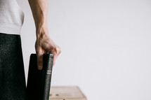 a man standing holding a Bible at his side 