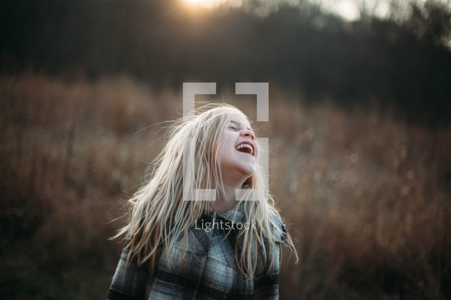 a girl laughing in a field 