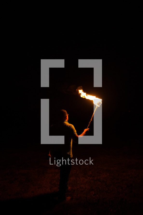 a man walking with a burning flame through darkness 