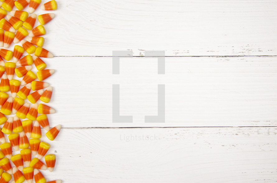 candy corn border on white wood background 