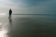 a man standing on wet sand on a beach 