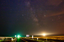 stars in a night sky and lights from a highway 