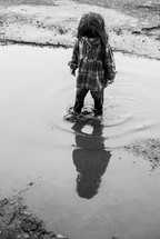 a little girl standing in a puddle 