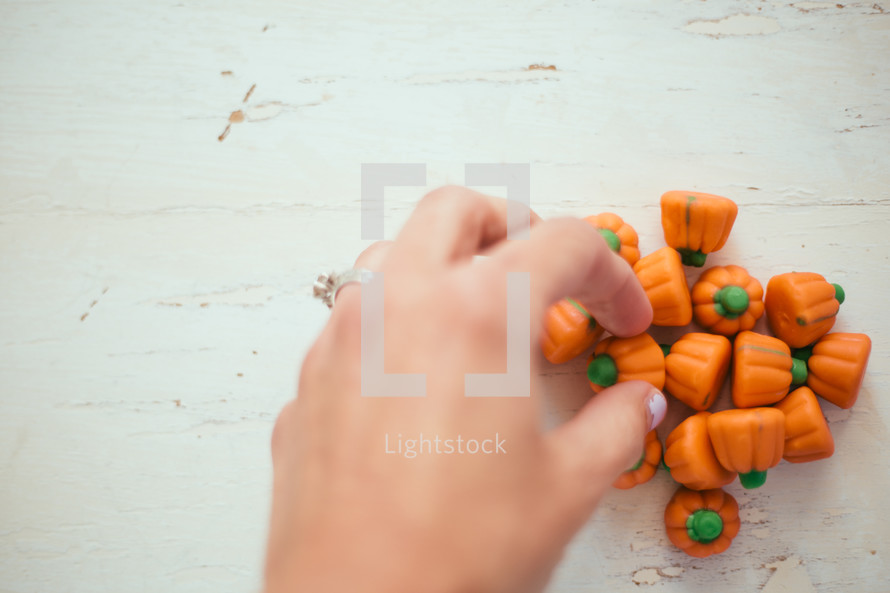 hand reaching for pumpkin candies 