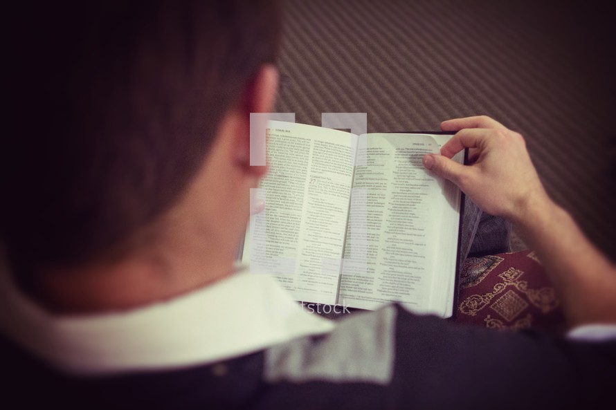 a man looking down reading a Bible 