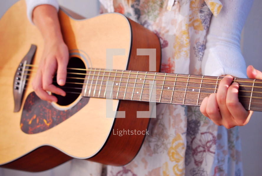torso of a woman playing an acoustic guitar 