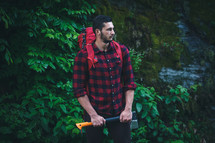 a man hiking carrying an ax outdoors 