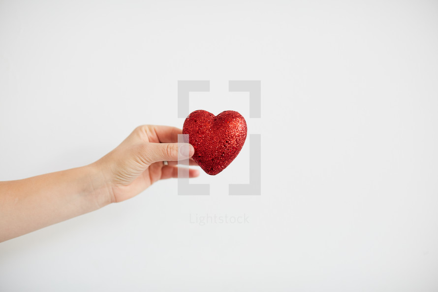 a woman holding out a red heart 
