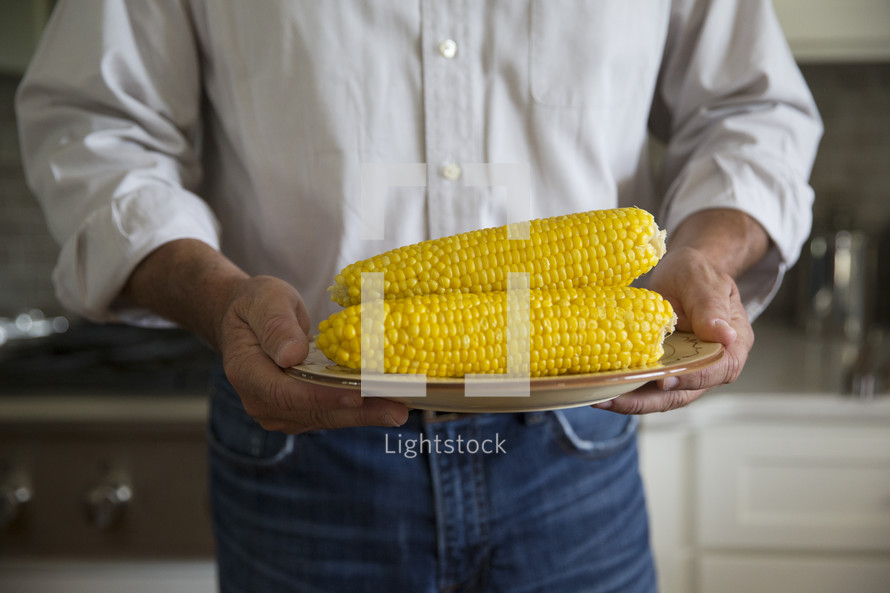 a man holding corn on the cob