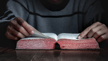a man reading a Bible at a table 