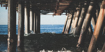 waves crashing into the pillars of a pier 