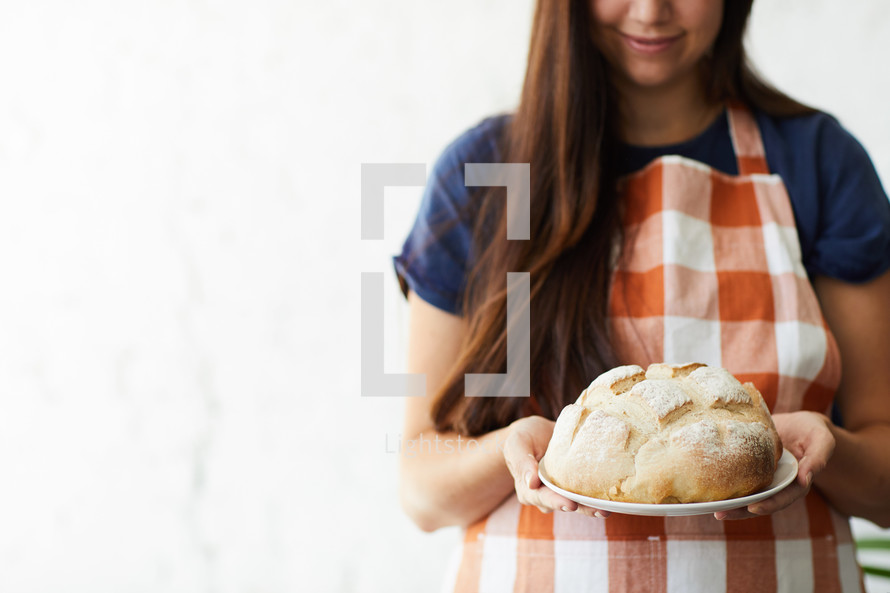 a woman holding a loaf of homemade bread 