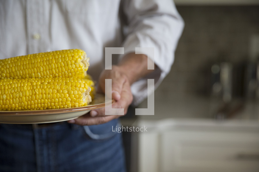 a man holding corn on the cob 