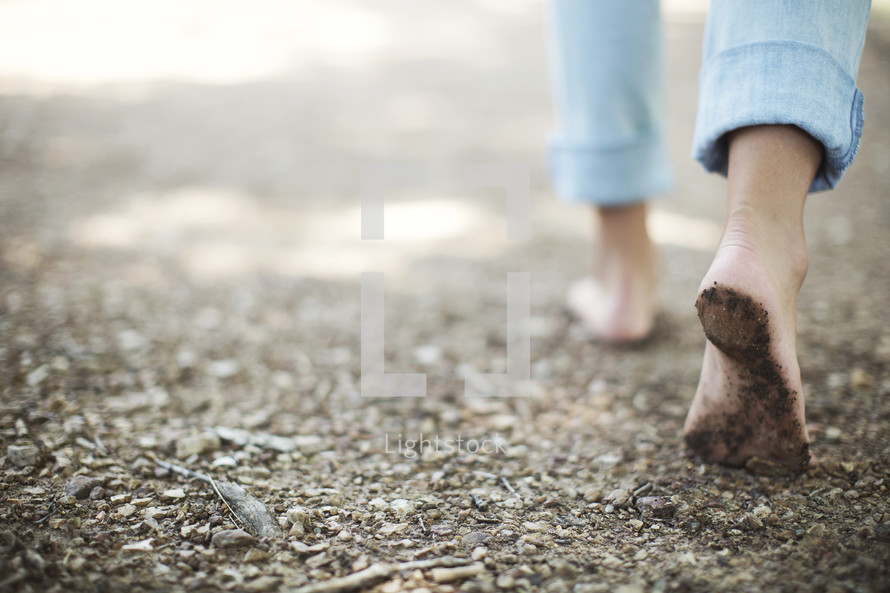 girl walking with bare feet on a trail.