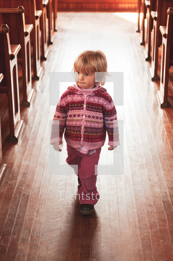 a toddler walking in the aisle of an empty church 