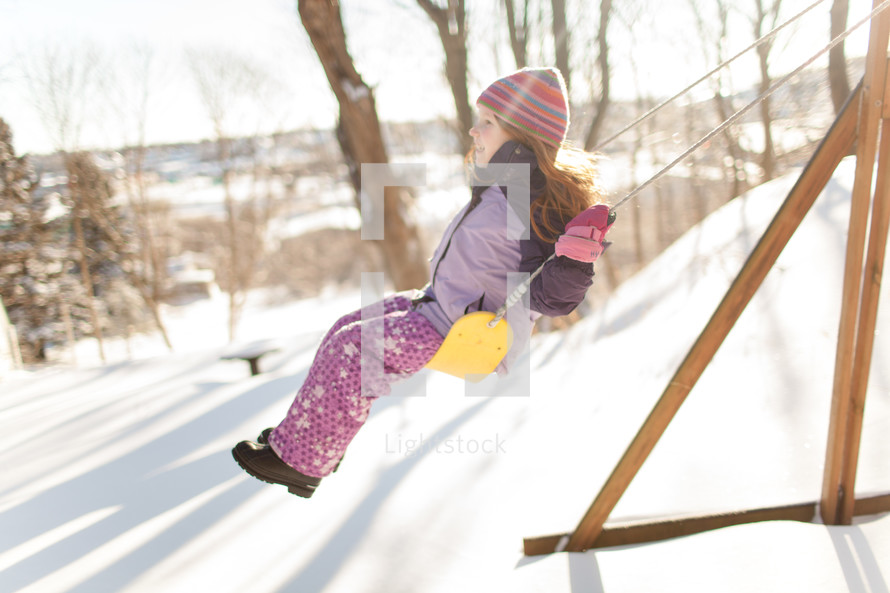 children on a backyard swing set in snow 