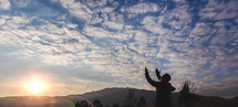 a man standing on a mountain with hands raised 