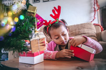 toddler girl with gifts under a Christmas tree 