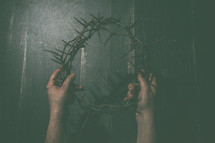 hands holding up a crown of thorns 