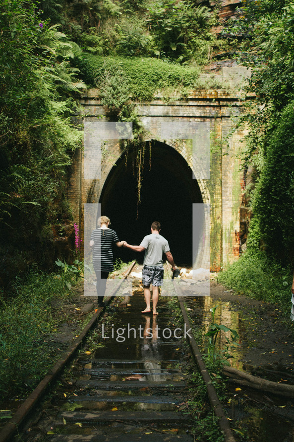 couple walking on old railroad tracks 