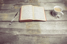 pen, opened Bible, and coffee mug 