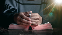 a man holding a beaded bracelet and praying 