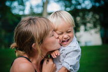 a mother kissing her laughing toddler 