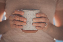 A woman's hands holding a white coffee mug