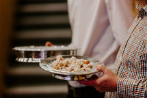 Man holding a communion bread plate.