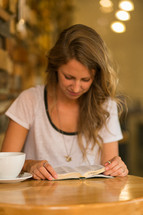 a woman reading a Bible in a coffee shop 