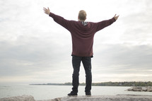 a man standing on a shore with outstretched arms