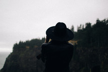 A woman in a hat looking at a mountain.