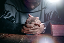 a man praying next to a closed Bible 