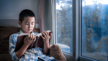 a boy reading a Bible in a window 