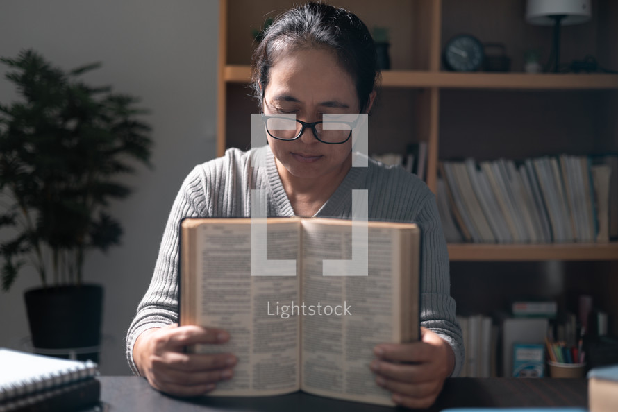 Woman praying while holding a bible