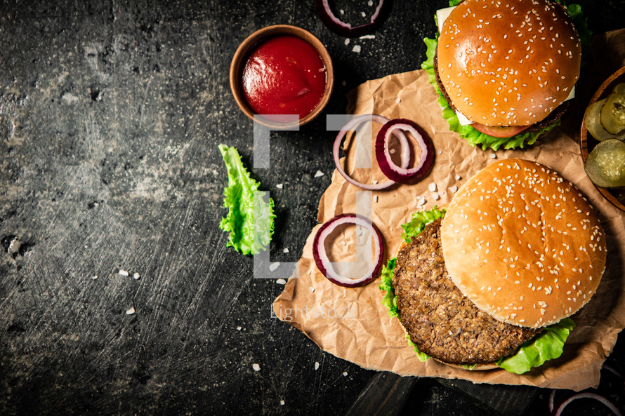 A burger on a stone board on a table. On a black background. High quality photo