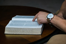 a man pointing to scripture while reading a Bible 