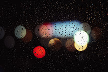 rain on a glass window on bokeh lights at night 