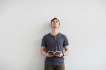 a man standing holding a Bible and looking up to God 