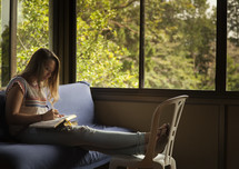girl reading a Bible on a couch 